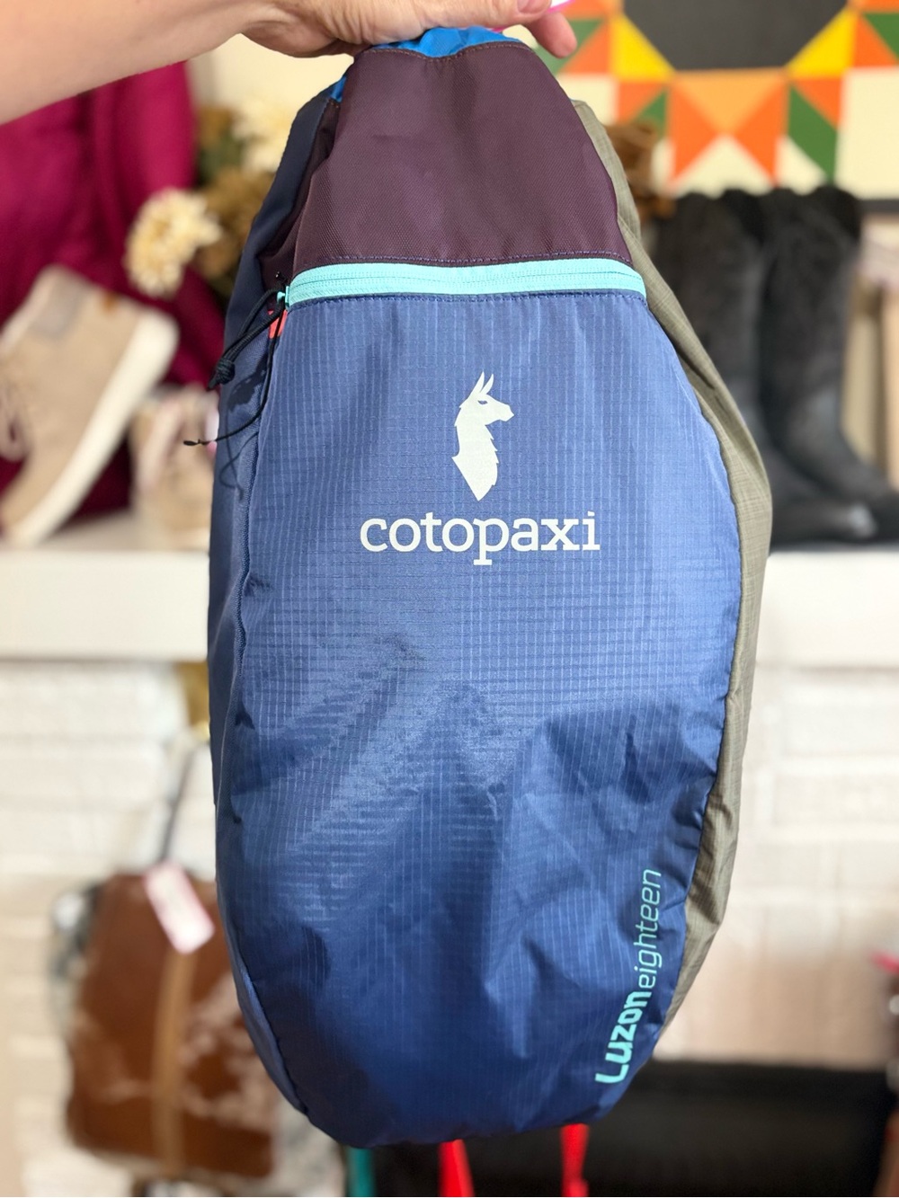 cotopaxi blue sling pack with teal trim and purple top